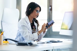 Doctor looking at phone at desk